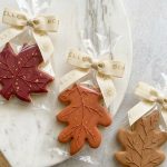 Autumn-themed sugar cookies decorated with detailed leaf designs, warm fall colours, and delicate gold accents.