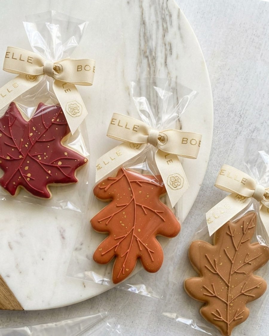 Autumn-themed sugar cookies decorated with detailed leaf designs, warm fall colours, and delicate gold accents.